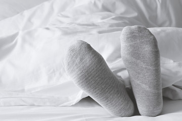 gray socks relaxing on the white bed