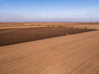Obraz premium Aerial shot of a farmer plowing stubble field
