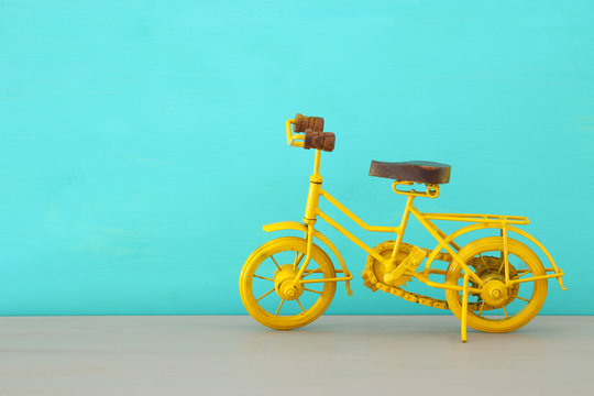 Vintage metal yellow bicycle toy over wooden table.