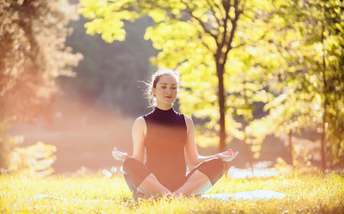 Yoga outdoor. Happy woman doing yoga exercises, meditate in the park. Yoga meditation in nature....