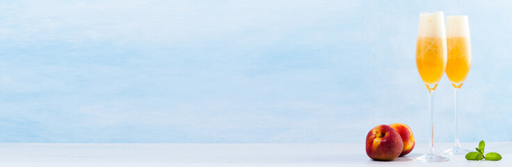 two glasses of champagne with a cocktail of Bellini and fresh peaches on a blue background. summer refreshing drink