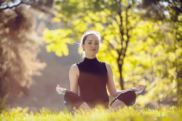 Yoga outdoor. Happy woman doing yoga exercises, meditate in the park. Yoga meditation in nature....