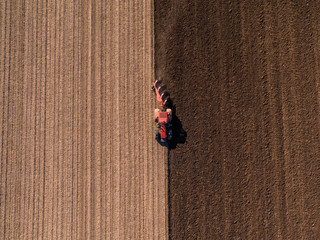Aerial shot of a farmer plowing stubble field - obrazy, fototapety, plakaty
