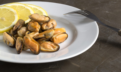 Mussels boiled on a white plate with lemon.