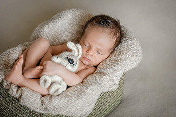 Newborn boy is sleeping in the basket with toy