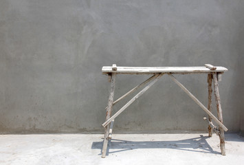Grey cement wall background with construction bench on floor