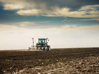 Obraz premium Farmer seeding, sowing crops at field. Sowing is the process of planting seeds in the ground as part of the early spring time agricultural activities.