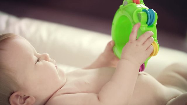 Naked baby lying with toy. Close up of female hands change diaper. Mother care. Infant hygiene concept