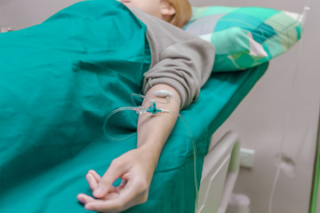 Patient is on drip receiving a saline solution in hospital.