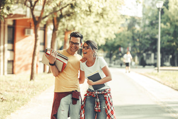 Young student couple going to college class.They walks trough university campus and laughing.