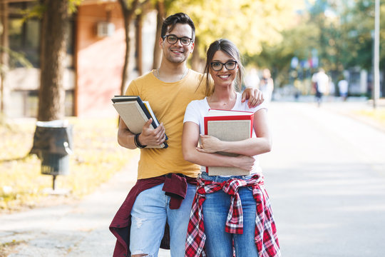 Young Student Couple Standing At The College Yard.