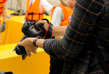 Photographers are checking photos after shooting, photographers photographed while wearing a life jacket, photographer checking camera on yellow background