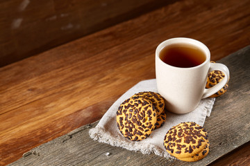 Cup of tea and chocolate chip cookies on white homespun napkin in country style, selective focus.