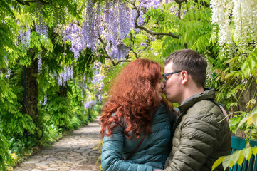 Kissing couple in wisteria garden