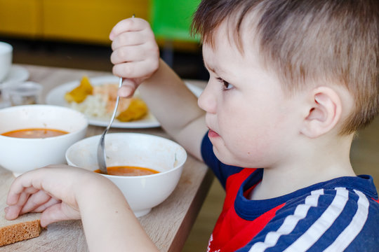 Little Boy Eating Soup With A Large Spoon