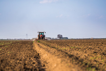 Obraz premium Farmer in tractor preparing land with seedbed cultivator as part of pre seeding activities in early spring season of agricultural works at farmlands.