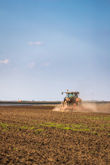 Farmer in tractor preparing land with seedbed cultivator as part of pre seeding activities in early spring season of agricultural works at farmlands.