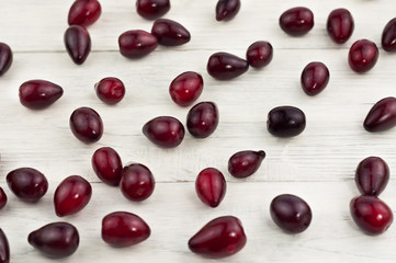 Red fresh raw cornel scattered on old white wooden rustic table