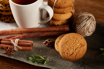 Traditional Christmas tea concept with a cup of hot tea, cookies, and decorations on a wooden table, selective focus