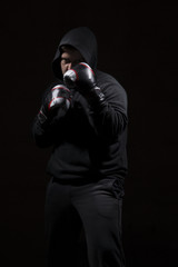 Male adult with black hoodie on black background. High resolution image concept for boxing and fighting industry.