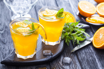 orange cocktail with ice and fresh mint on a black wooden table