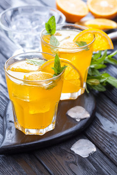 orange cocktail with ice and fresh mint on a black wooden table