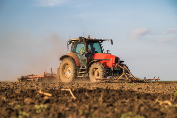 Fototapeta premium Farmer in tractor preparing land with seedbed cultivator as part of pre seeding activities in early spring season of agricultural works at farmlands.