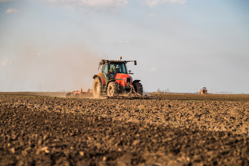 Fototapeta premium Farmer in tractor preparing land with seedbed cultivator as part of pre seeding activities in early spring season of agricultural works at farmlands.