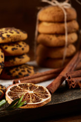 Christmas composition with pile of cookies, cinnamon and dried oranges on wooden background, close-up.