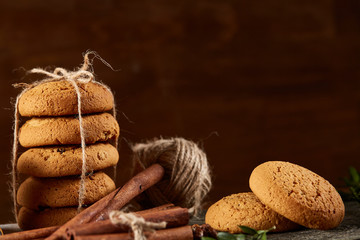 Christmas composition with pile of cookies, cinnamon and dried oranges on wooden background, close-up.