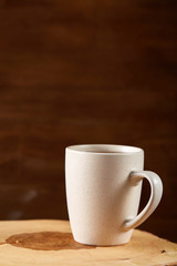 White cup of hot tea on an old log over rustic wooden background, selective focus