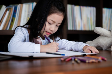 cute girl smiled and sitdown to drawing a book in the library, children concept, education concept