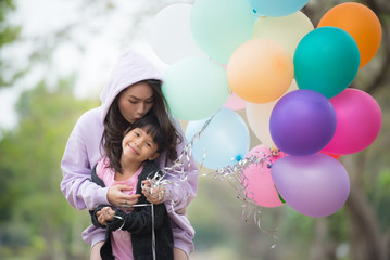 cheerful little child with mother having fun outdoors with many colorful balloons, happy family life. summer holidays, mother and child with colorful balloons
