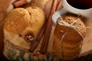 Christmas still life with assortment of cookies, cinnamon and dried oranges on a log, close-up, selective focus.