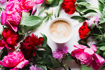 Morning coffee and beautiful pink and red peony flowers on white table top view in flat lay style. Cozy breakfast on Mother or Woman day.