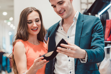 Man and woman thinking about buying pair of blue shoes