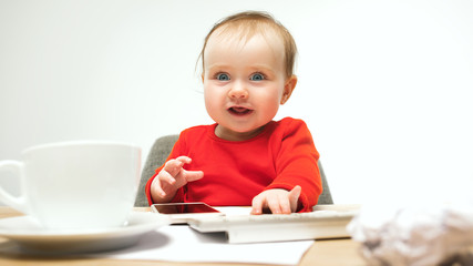 Happy child baby girl toddler sitting with keyboard of computer isolated on a white background