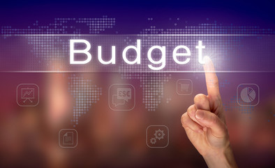 A hand selecting a Budget business concept on a clear screen with a colorful blurred background.