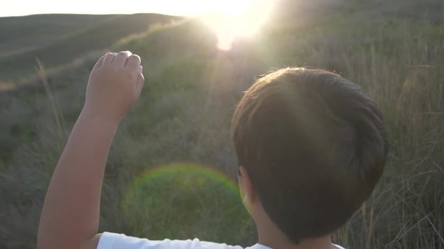 Boy rize up his hand to touch the sun