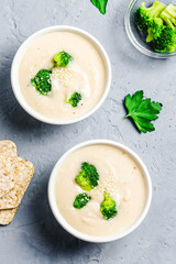 Artichoke white bean broccoli soup puree in a bowl on blue concrete background. Top view, space for text. 