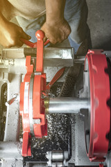 the worker use  pipe threading machinesteel in industrial shop.