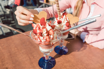 Women eating ice cream in restaurant on sunny day with strawberries