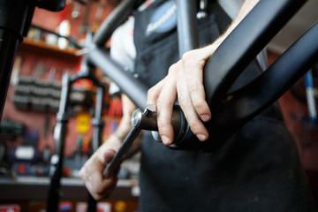 Picture of man mending part of bicycle in workshop.