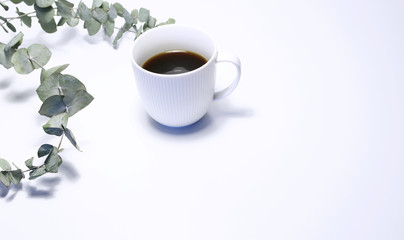Styled stock photo. Feminine still life composition with cup of coffee, and bouquet of eucalyptus branches on white background. Summer rustic scene, product mockup.