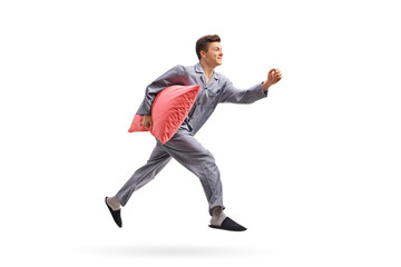 Teenage boy in pajamas holding a pillow and running
