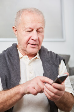 Senior tippt eine SMS auf dem Smartphone