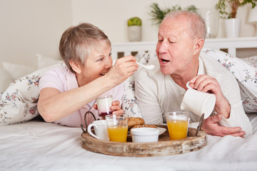 Glückliches Senioren Paar frühstückt im Bett
