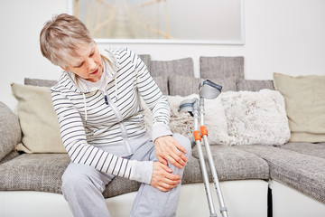 Ältere Frau mit Krücken und Knieverletzung