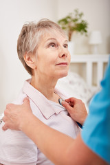 Krankenschwester horcht Seniorin ab