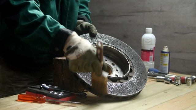 Un homme degraisse et d&eacute;poussi&egrave;re un disque de frein